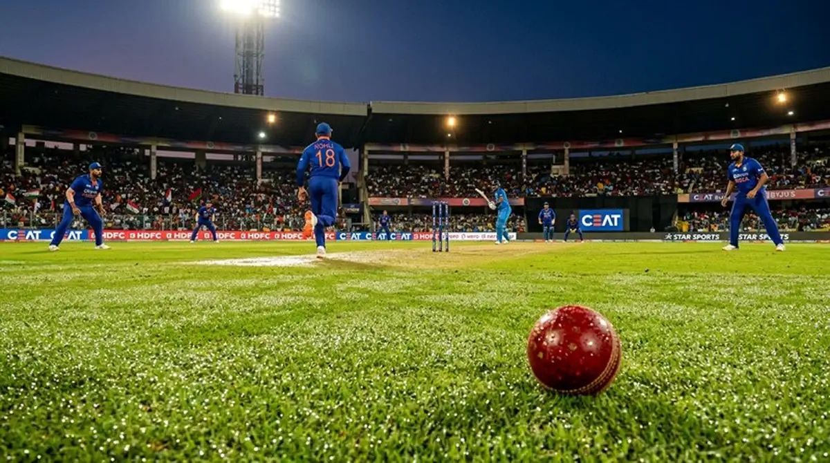 Partita di cricket serale con luci dello stadio e condizioni di rugiada